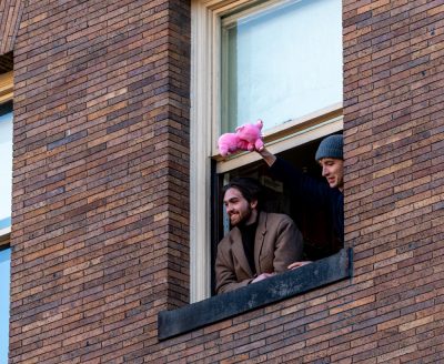 两个人从窗户往外看。一个人手里拿着一个粉红色的毛绒玩具